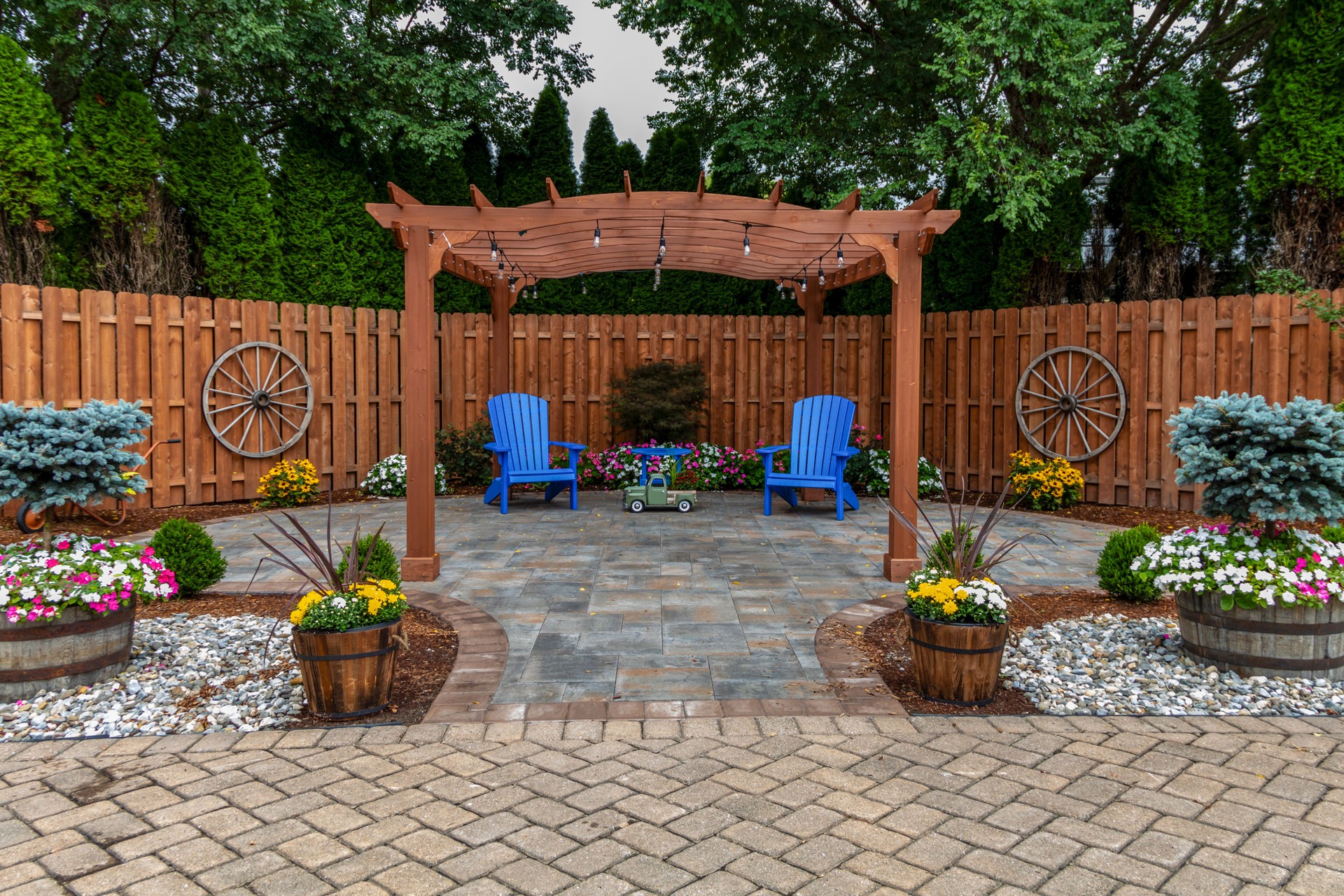 Wooden pergola on pavers landscape design with select ornamental flowers and evergreens backyard oasis